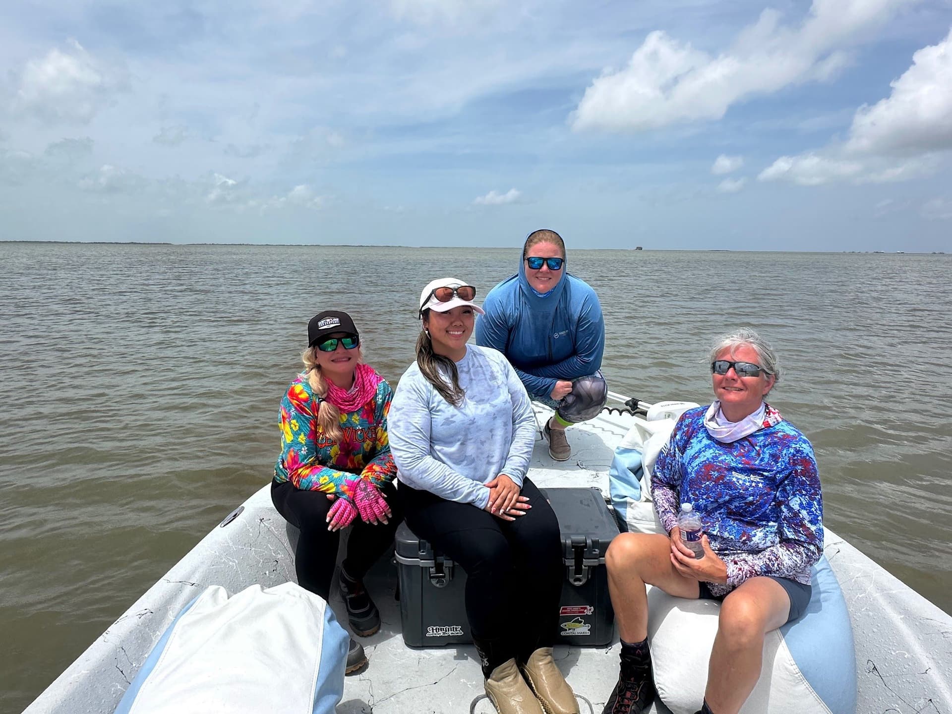  Four women in fishing shirts on a bay boat on open coastal water during a Texas saltwater fishing trip