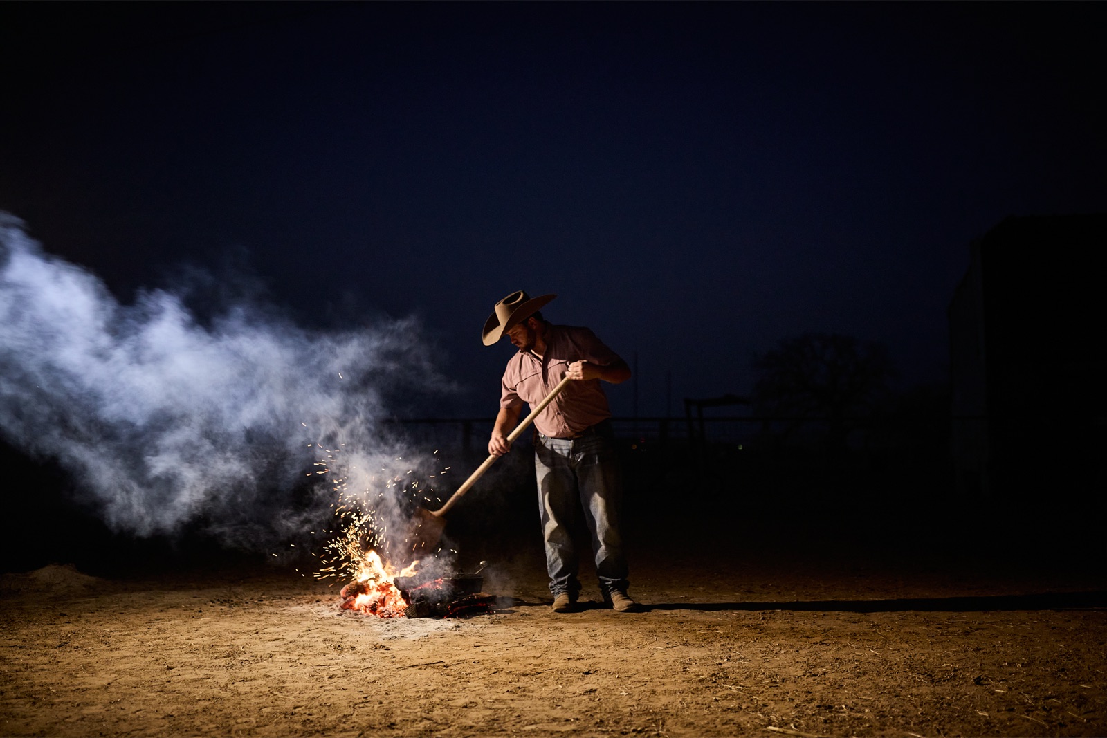 Rancher tending a campfire under a night sky